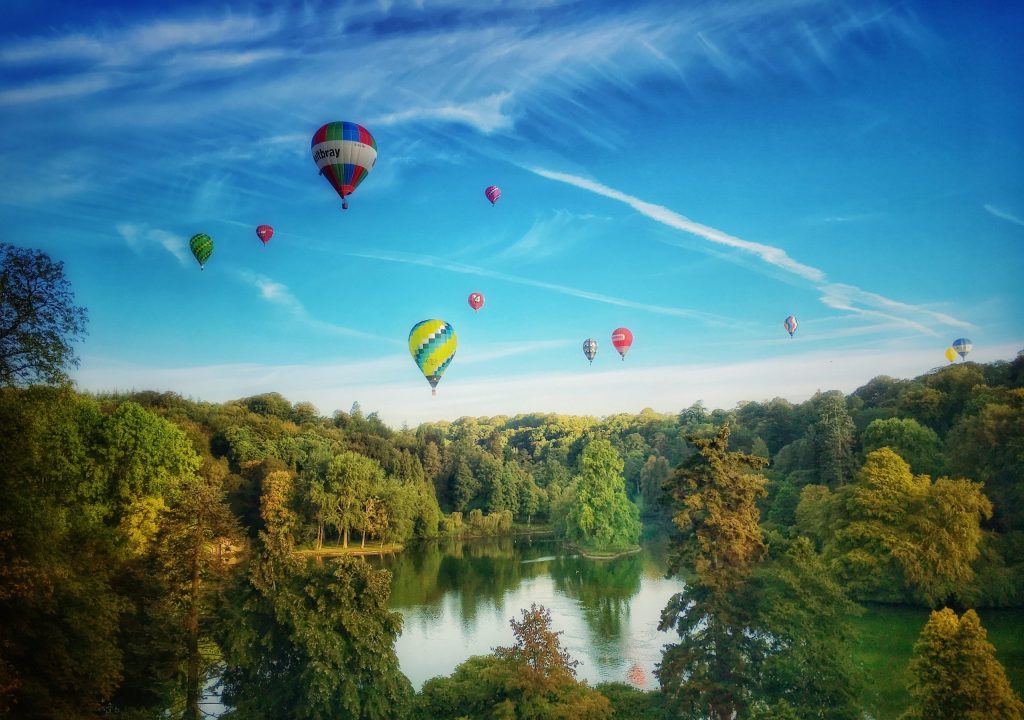 Photo of the Stourhead Gardens with hot air balloons from the Longleat Air Races taken by the author. Photo used in the author's article about best insider travel tips.