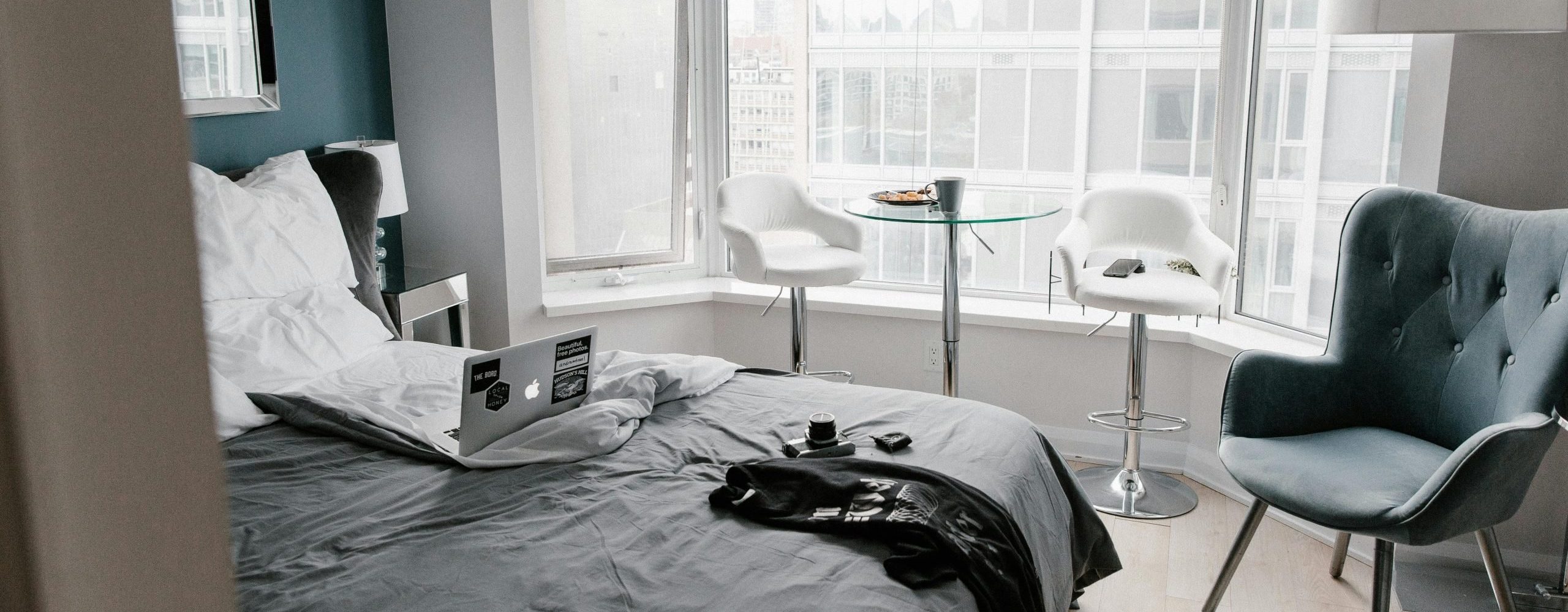 Image of a hotel room with an open laptop on the bed. Photo used to illustrate working while traveling and 5 business travel tips to add vacation into your work trips. Photo by Andrew Neel