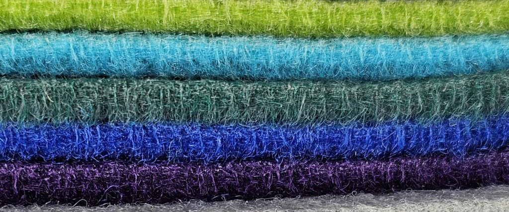 Base layers, especially wool, are essential when you dress for cold weather. This image shows a stack of colorful wool fabrics. Photo by Ann H