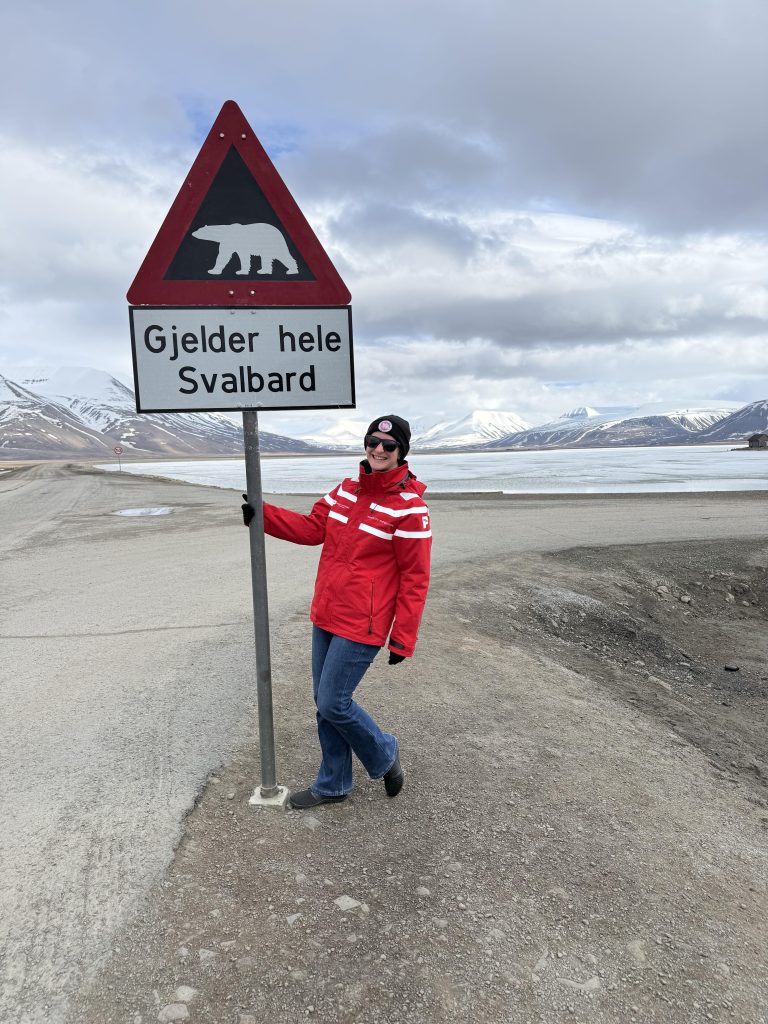 Arctic or Antarctic? The author is pictured on Svalbard beneath one of the Polar Bear signs.